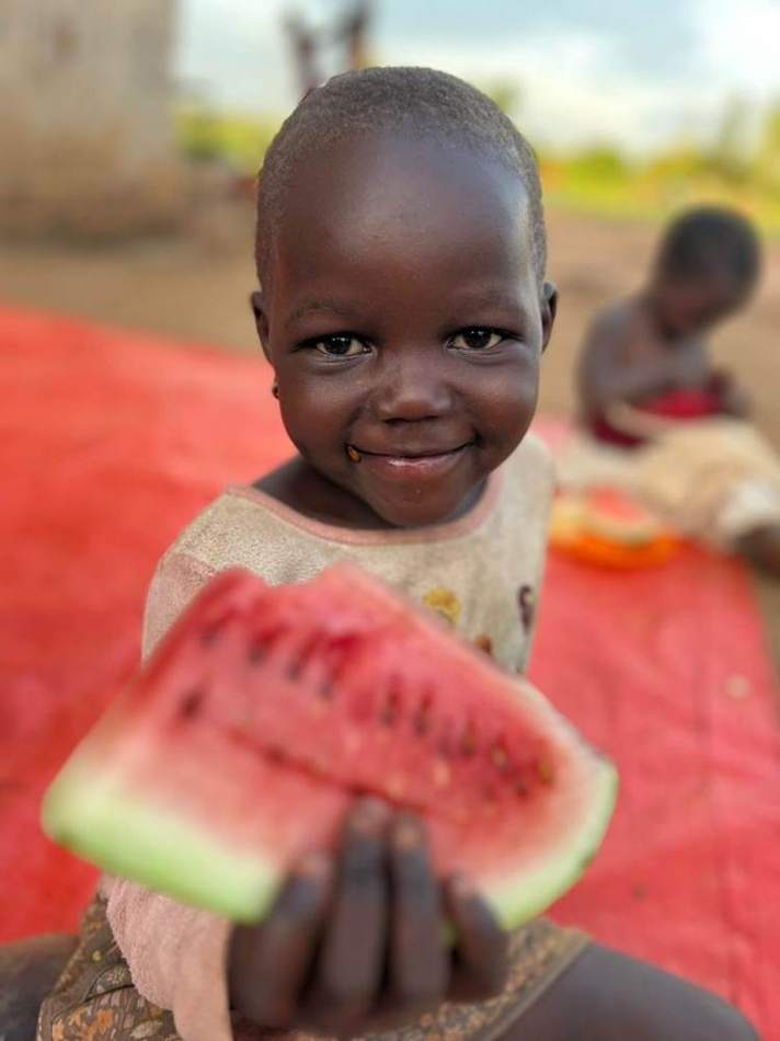 A child in Imuli Village holding fresh watermelon